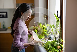 Beautiful woman watering plants at home